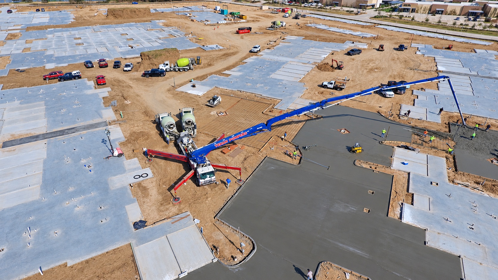 Concrete pump and crews placing a large slab